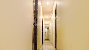 A long, narrow hallway with a shiny floor and light-colored walls. - Fabexpress Gateway Inn (Mumbai)