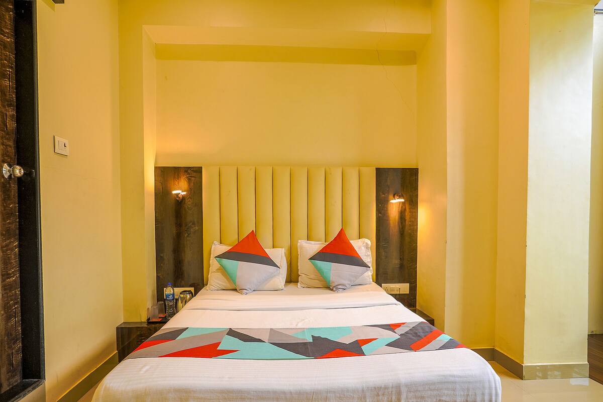 Quarto de hotel com uma cama, duas mesas de cabeceira e cabeceira.