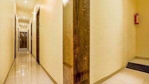 A hotel corridor with a polished floor, a wooden column, and a fire extinguisher on the wall. - Fabexpress Gateway Inn (Mumbai)