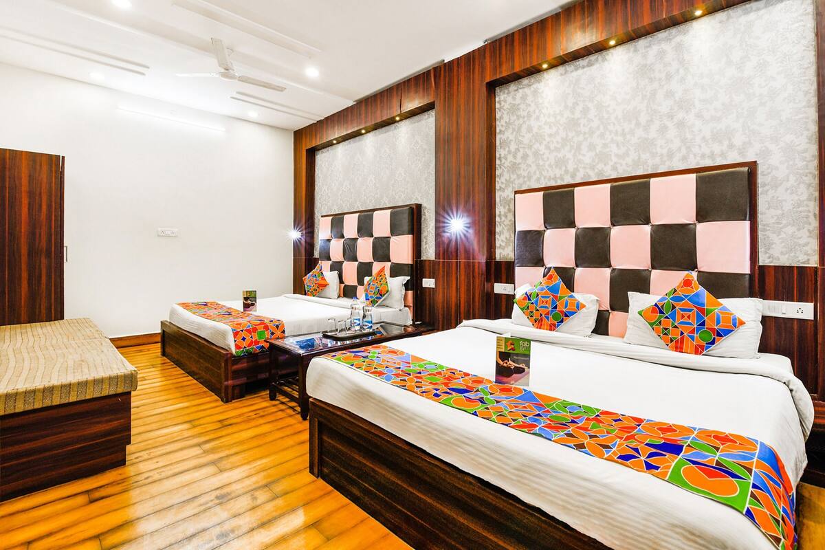 A hotel room with two beds, a wooden floor, and a large mirror on the wall.
