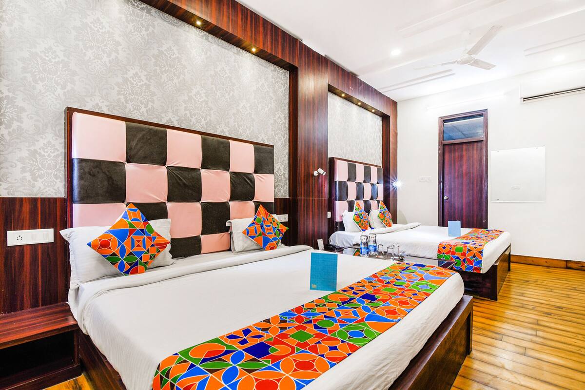 A hotel room with two beds, a large mirror, and a wooden floor.