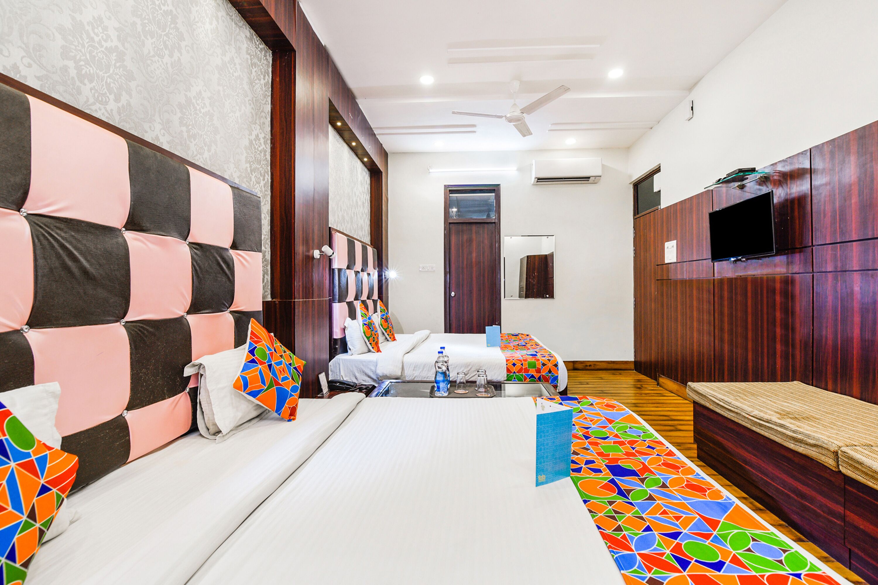 A hotel room with a large bed, a sofa, a TV, and a ceiling fan.