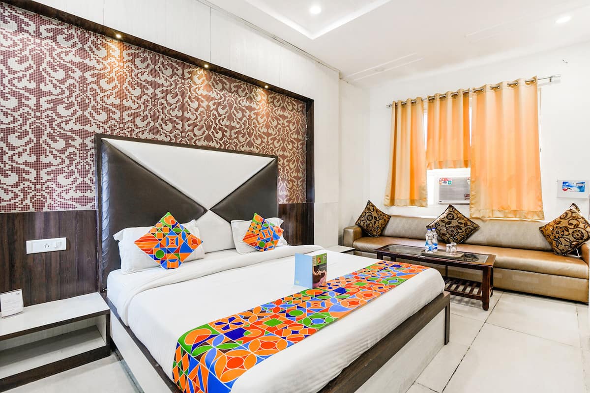 A hotel room with a large bed, a sofa, a coffee table, and a patterned headboard.