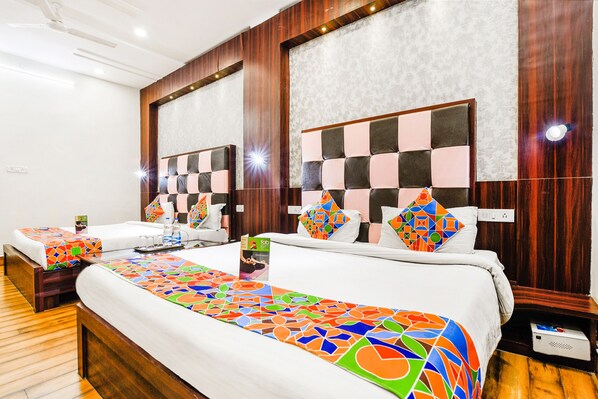 A hotel room with two beds, a large colorful bed runner, wooden paneling, and a mirror above the beds.