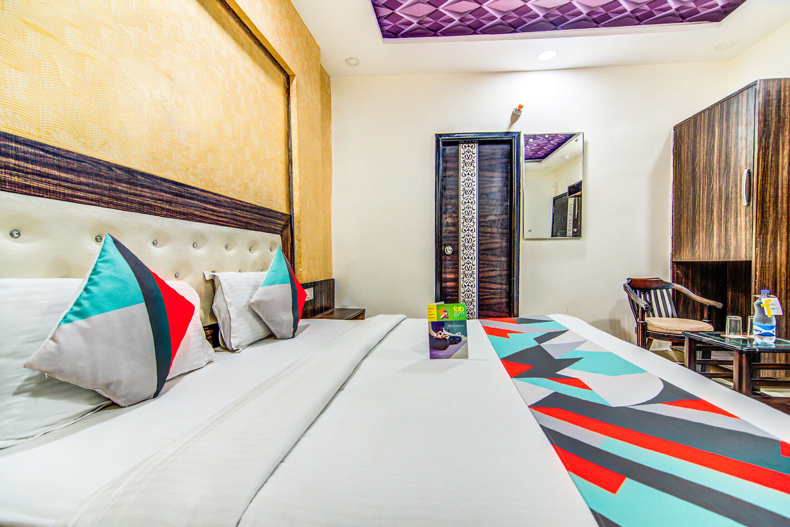 Una habitación de hotel con una cama grande, un cabecero de madera, una mesita con una silla y un espejo en la pared.