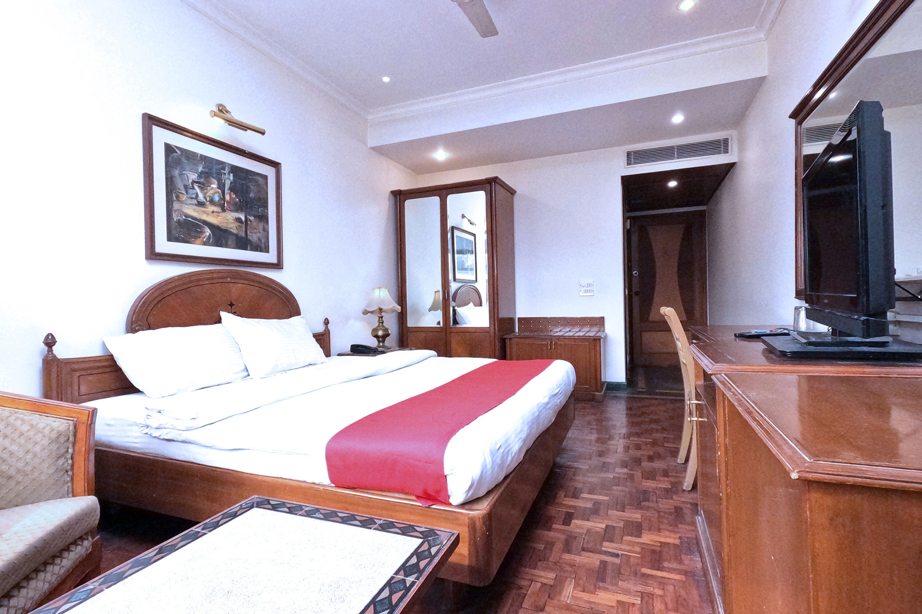 Una habitación de hotel con una cama grande, un escritorio, una silla, un televisor y un espejo.