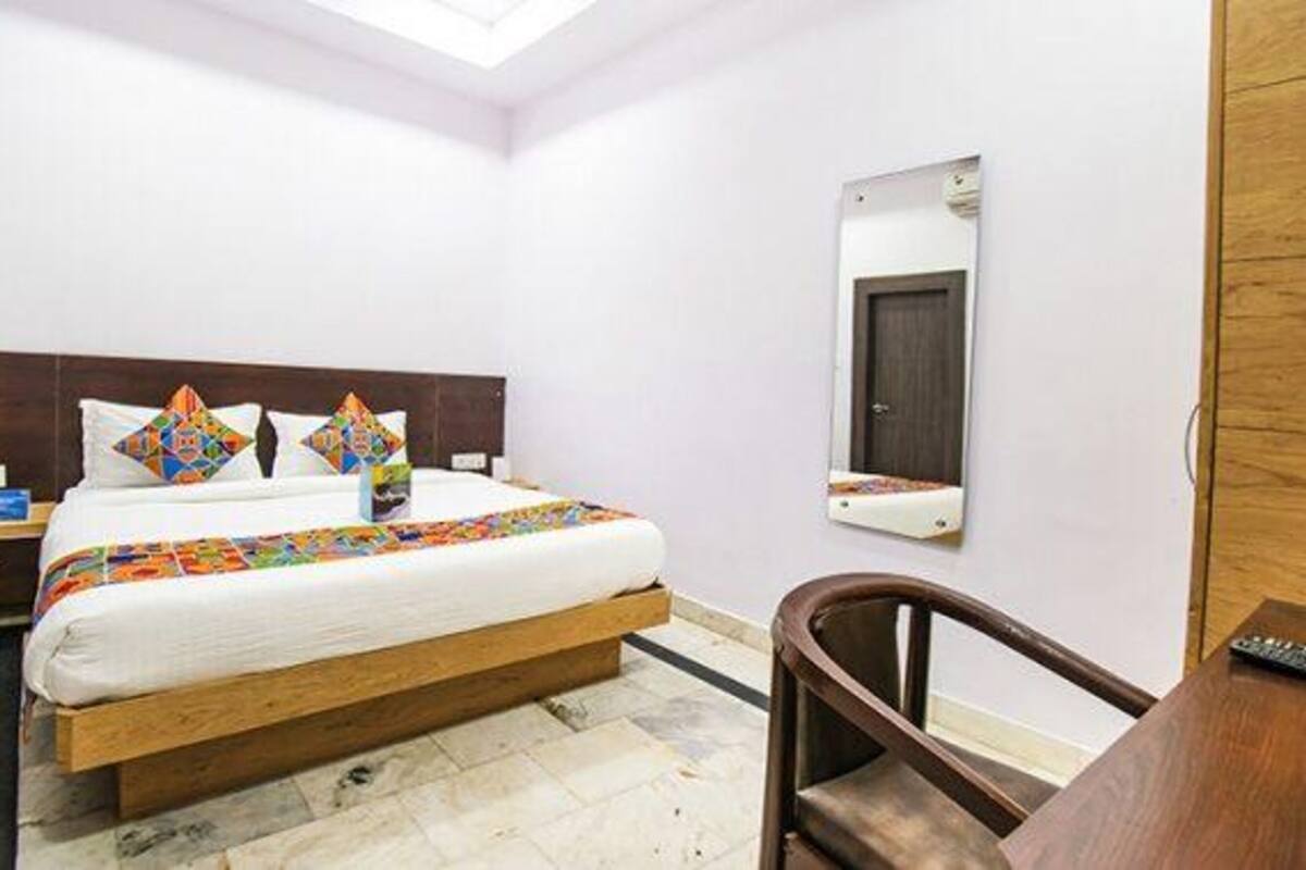 A hotel room with a bed, a nightstand, a chair, a desk, and a mirror.