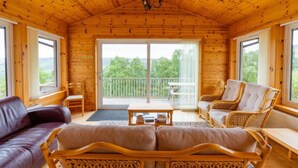 Een gezellig houten blokhut interieur met een bank, stoelen en een balkon met een prachtig uitzicht.