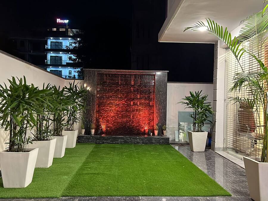 Un jardín en la azotea con césped artificial, plantas en macetas y una fuente de agua.