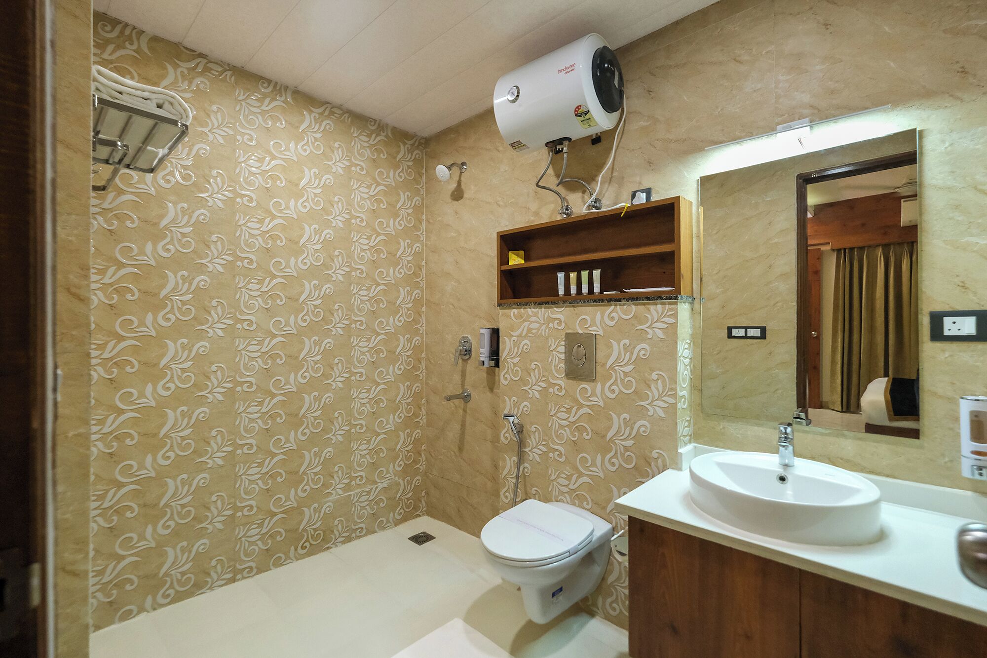 Baño con inodoro, lavabo y ducha. Hay un perchero y una repisa con artículos de aseo.