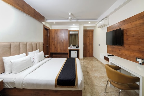 A hotel room with a bed, a desk, a chair, a television, and a wardrobe. - Hotel Golf Inn (Gurugram)