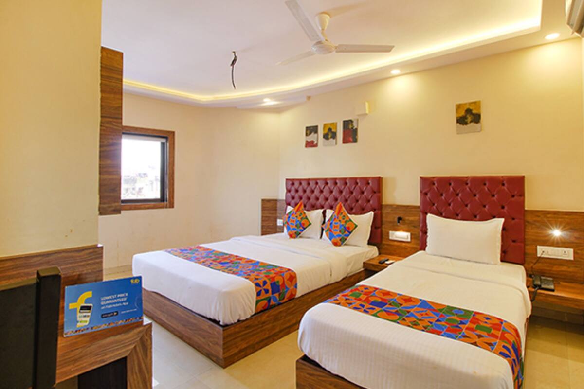 A hotel room with two beds, a window, and a ceiling fan.