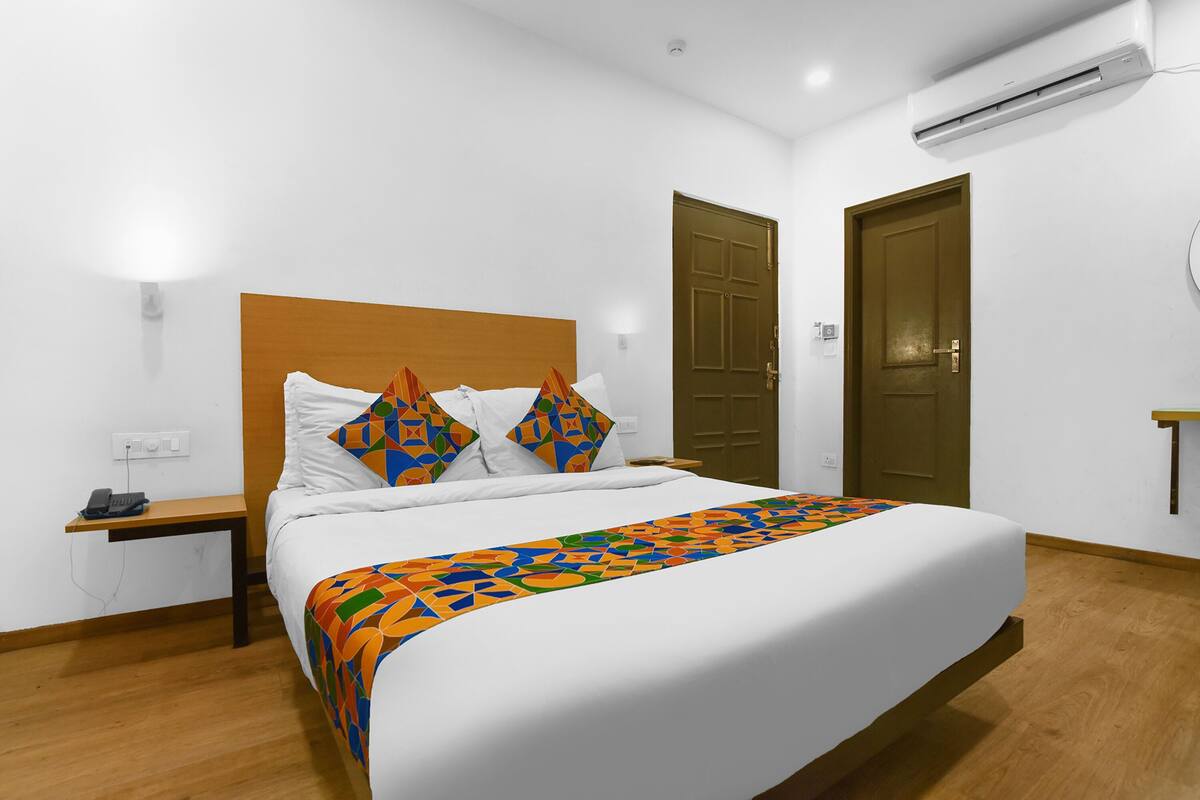Ein Hotelzimmer mit Bett, Nachttisch mit Telefon, Wand-Klimaanlage und zwei Türen.