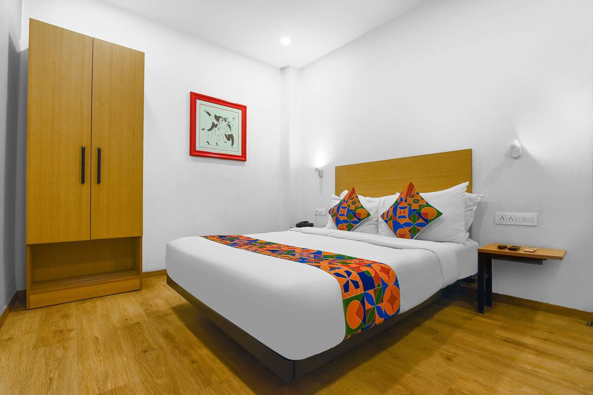 Ein Schlafzimmer mit einem Bett, einem Holzschrank, einem Nachttisch und einer Wandleuchte.