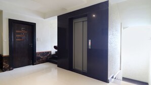 A modern hallway with a black elevator, a door labeled '309', and a marble-tiled floor. - Fabhotel Nera Regency (Hyderabad)