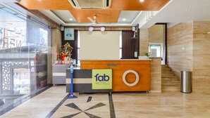 A hotel reception area with a reception desk, a clock, and a ceiling fan. - Fabhotel Nera Regency (Hyderabad)