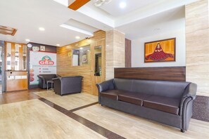 A lobby with a reception desk, a Grand Spicy Bawarchi sign, a brown leather sofa, and a framed artwork on the wall. - Fabhotel Nera Regency (Hyderabad)