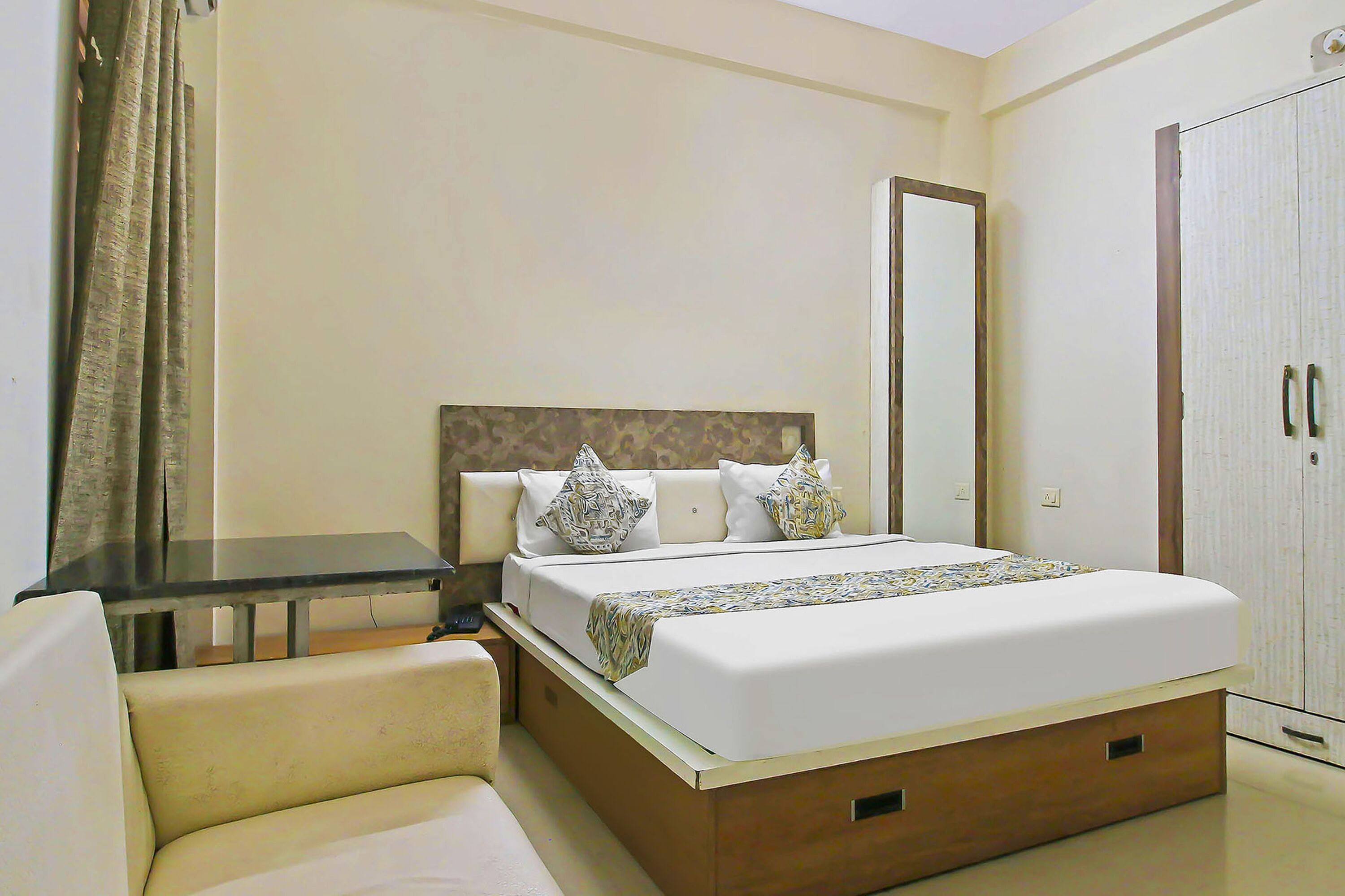A hotel room with a bed, a desk, a chair, and a wardrobe.