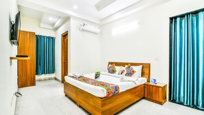 A modern hotel room with a wooden bed, a flat-screen TV, an air conditioning unit, and teal curtains. - Fabhotel Merriment (Noida)