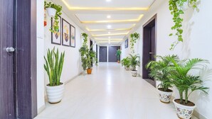 A hallway with potted plants, framed artwork, and recessed lighting. - Fabhotel Skyland (Ahmedabad)