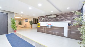 A hotel reception area with a reception desk, a clock, and a potted plant. - Fabhotel Skyland (Ahmedabad)
