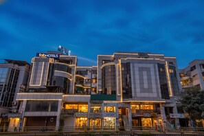 A modern hotel with a prominent 'fabHOTELS' sign, multiple floors, and illuminated storefronts.