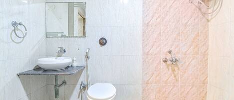 A bathroom with a sink, mirror, toilet, and shower.