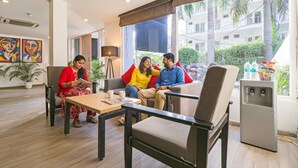 A modern hotel lobby with a seating area, a coffee table, and a refrigerator. - Fabhotel Destiny Inn (Gurugram)