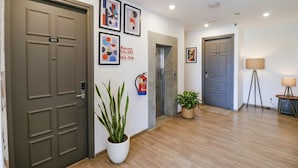 A hotel lobby with a wooden floor, a fire extinguisher, a potted plant, and framed artwork on the walls. - Fabhotel Destiny Inn (Gurugram)