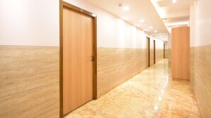 A corridor with wooden doors and marble flooring. - Fabhotel Stay Inn International (Kolkata)