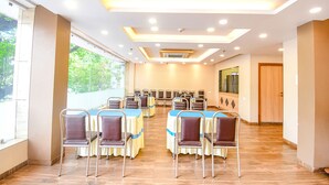 A conference room with rows of chairs and tables, large windows, and a modern ceiling design. - Fabhotel Stay Inn International (Kolkata)