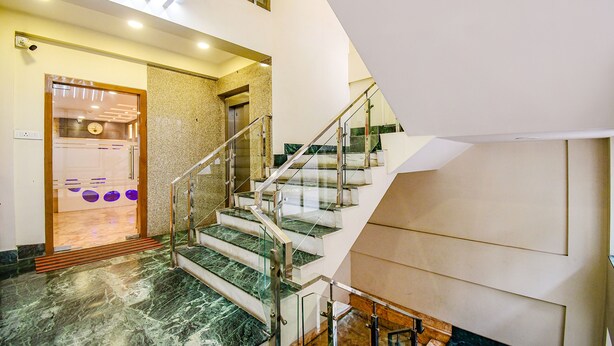 A modern hotel lobby with a marble staircase, a reception desk, and a glass elevator. - Fabhotel Stay Inn International (Kolkata)