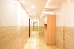 A long, narrow hallway with wooden paneling on the walls and a marble floor. - Fabhotel Stay Inn International (Kolkata)