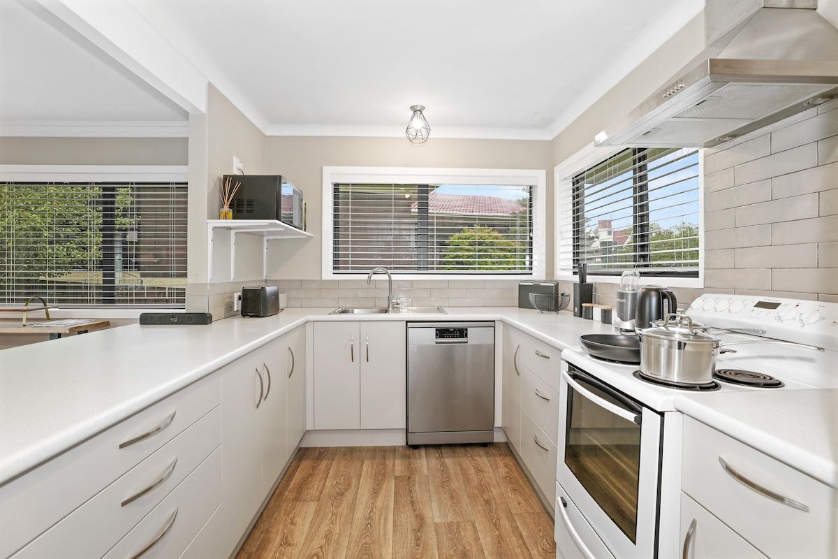 A modern kitchen with white cabinetry, a stainless steel dishwasher, and a built-in oven.