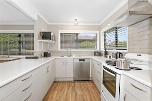 A modern kitchen with white cabinetry, a stainless steel dishwasher, and a built-in oven.