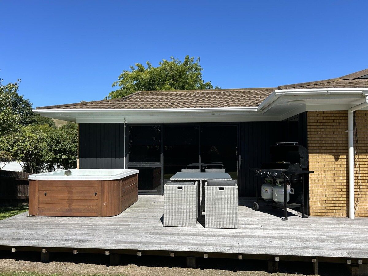 An outdoor patio with a hot tub, seating, and a grill area.