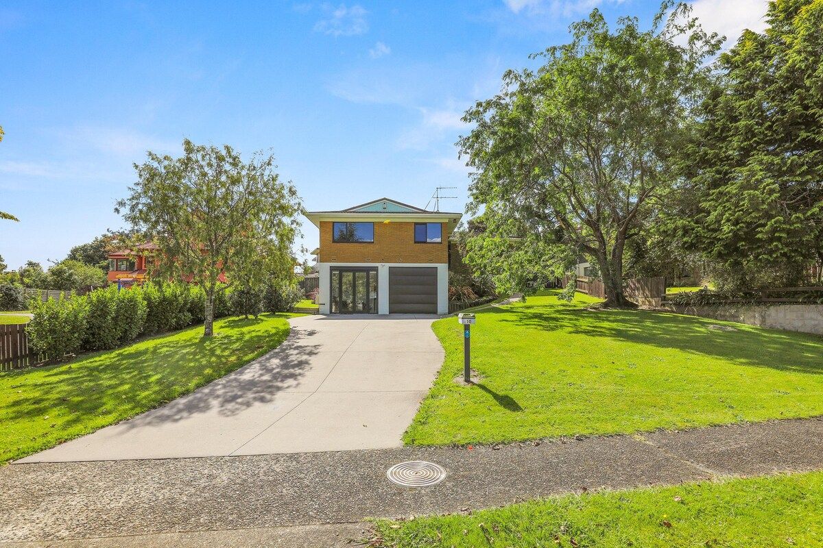 A two-story residential house with a garage, surrounded by a well-maintained lawn and trees.