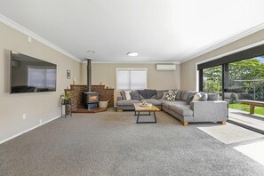 A living room with a fireplace, a grey sofa set, a coffee table, and a large window.