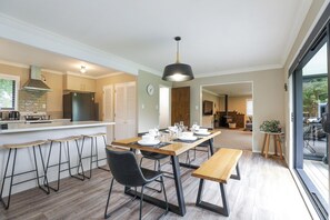 Une cuisine moderne dotée d’un îlot central, de tabourets de bar, d’une table à manger pour quatre personnes et d’un banc.