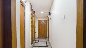 A narrow hallway with wooden doors on both sides, a marble floor, and a wooden door at the end. - Fabhotel The Eden Ruby (Kolkata)