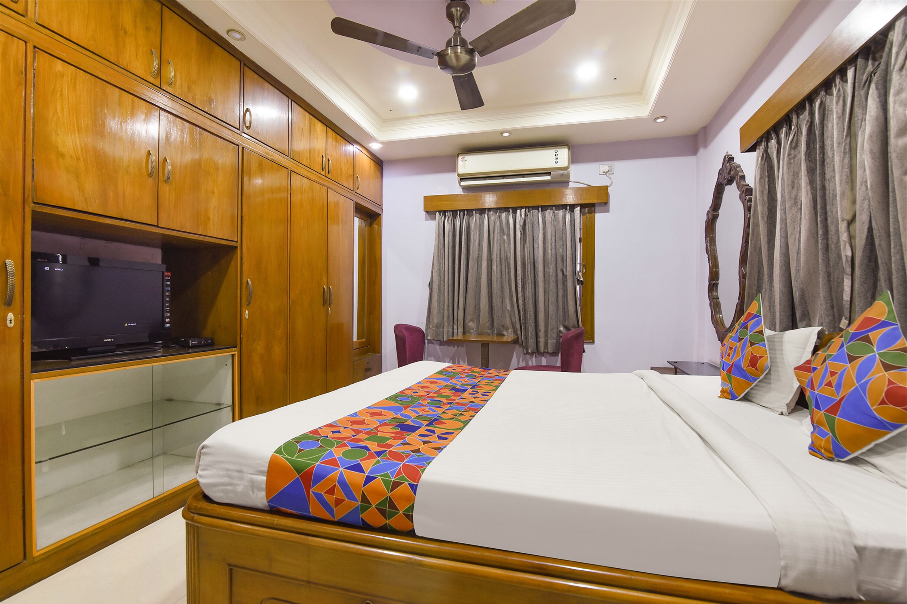 A bedroom with a bed, wooden wardrobe, and a ceiling fan.