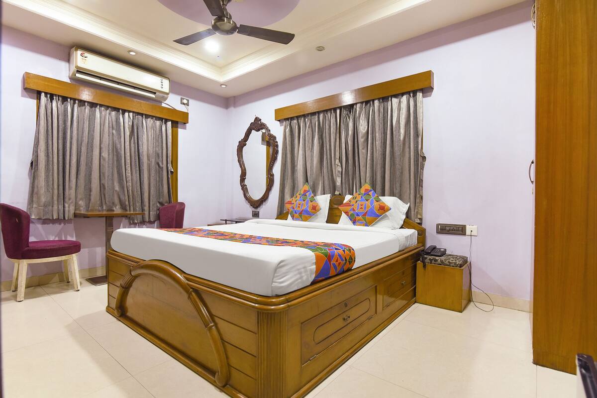 A bedroom with a wooden bed, grey curtains, a ceiling fan, and a bedside table.