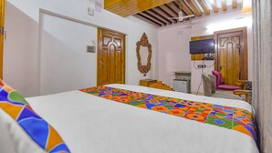 A hotel room with a large bed, wooden doors, a television, and a small desk. - Fabhotel The Eden Ruby (Kolkata)