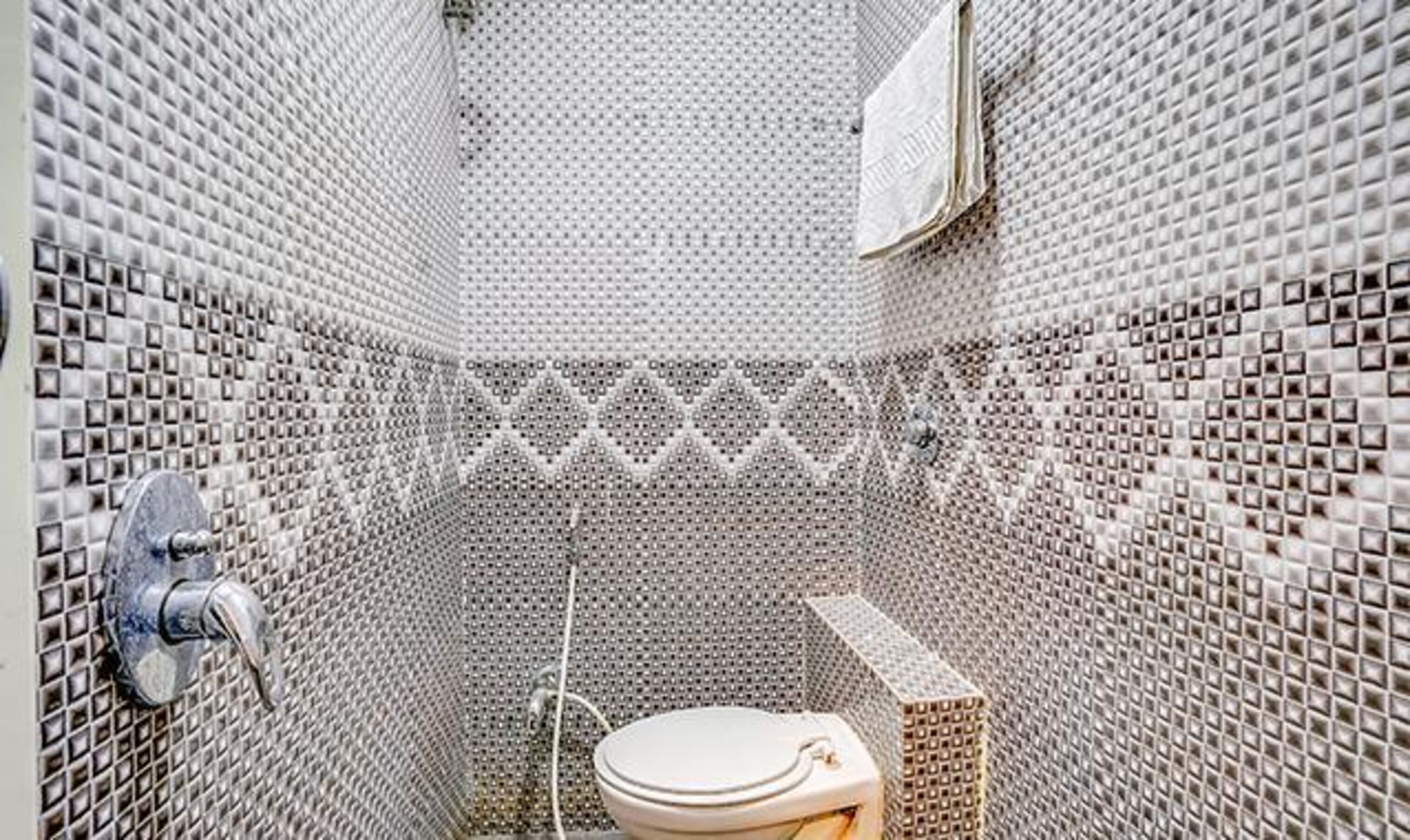 Ein Badezimmer mit gefliesten Wänden, einer Toilette und einer Duschkabine.