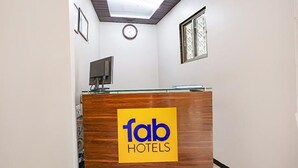 A reception desk with a 'fab hotels' sign, a clock, and a window with patterned glass. - FabHotel Comfort stay (Mumbai)