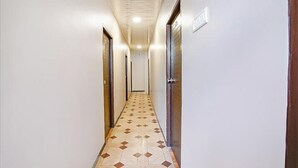 A narrow hallway with patterned floor tiles, white walls, and doors on both sides. - FabHotel Comfort stay (Mumbai)
