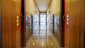 Un couloir élégant, avec des portes en bois portant les numéros G05 et G02, qui mène à un espace intérieur lumineux.