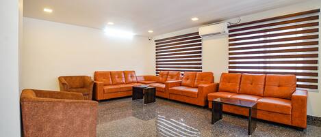 Un hall con zona de estar que incluye un conjunto de sofás y sillones, una mesa de centro y un suelo de piedra pulida.