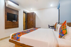 A hotel room with a bed, a television mounted on the wall, a wardrobe, and a desk with a chair. - Fabhotel Blue Marine (Indore)
