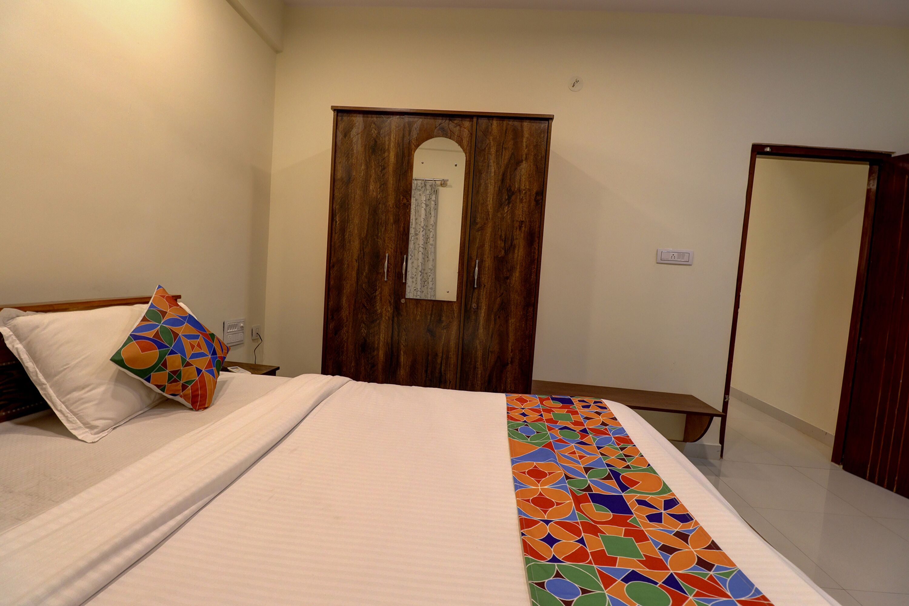 Een slaapkamer met een bed, een houten garderobe en een spiegel.